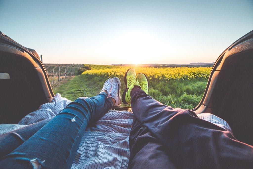 Couple sitting in the back of RV looking into field