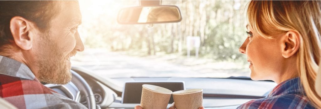 Couple in car drinking coffee