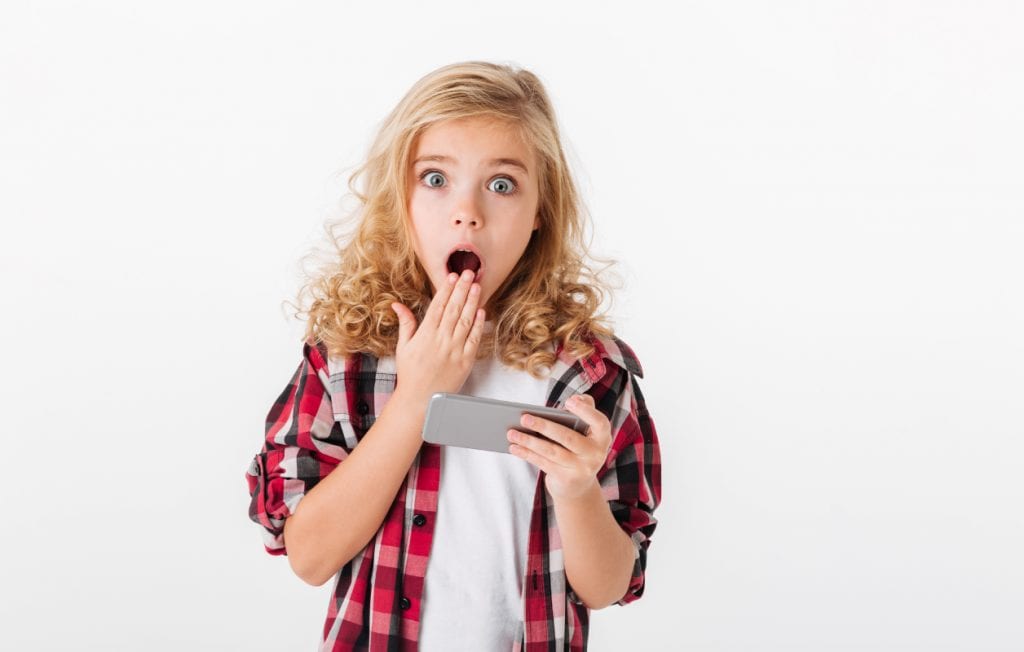 little girl shocked and surprised while looking at her phone