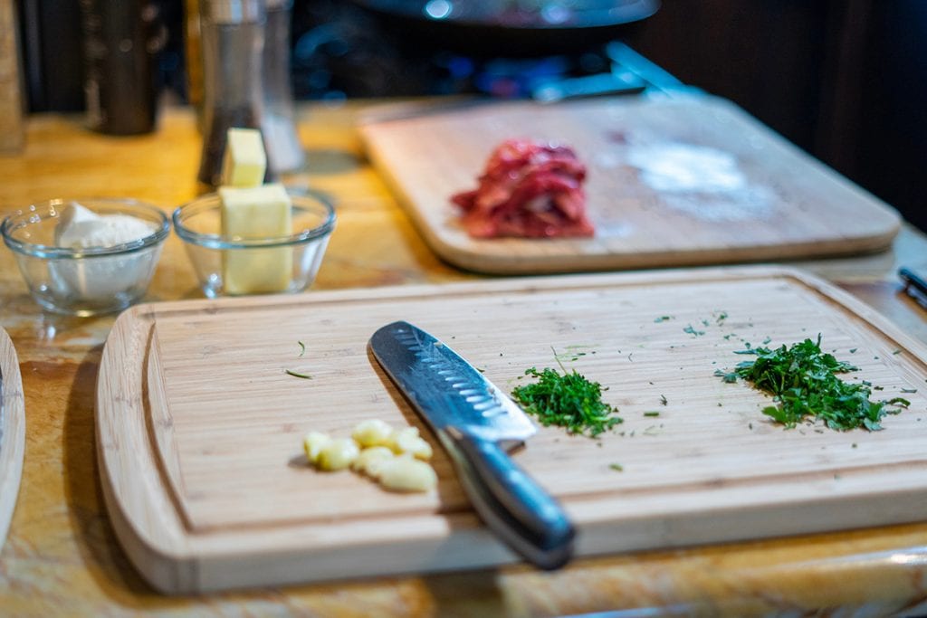 knife and cutting board with garlic and other herbs