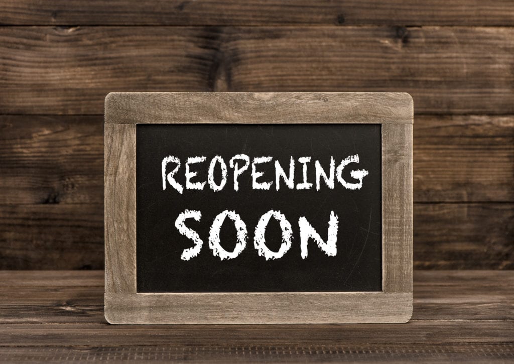 Chalkboard on wooden background. Reopening soon text